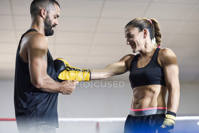 Тренер надевает боксерские перчатки на женщину-боксера — стоковое фото