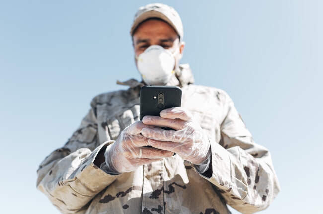 Soldat mit Gesichtsmaske bei Notoperation mit Smartphone — Stockfoto