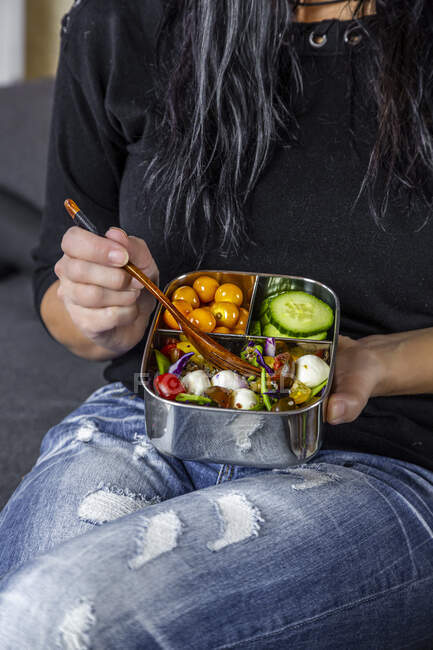 Parte centrale della donna seduta a mangiare dalla scatola del pranzo — Foto stock