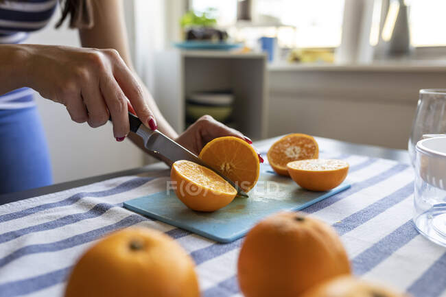Mujer rebanando naranjas frescas para jugo de naranja recién exprimido - foto de stock