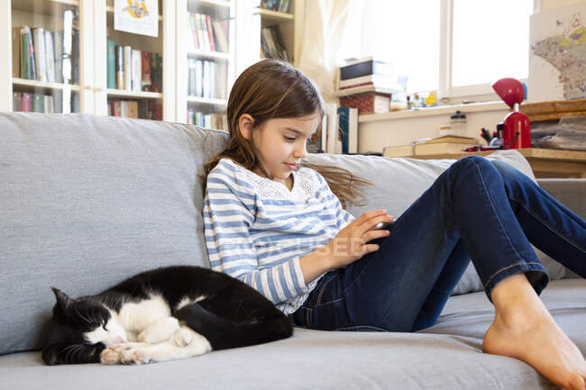 Ragazza seduta sul divano utilizzando tablet digitale — Foto stock