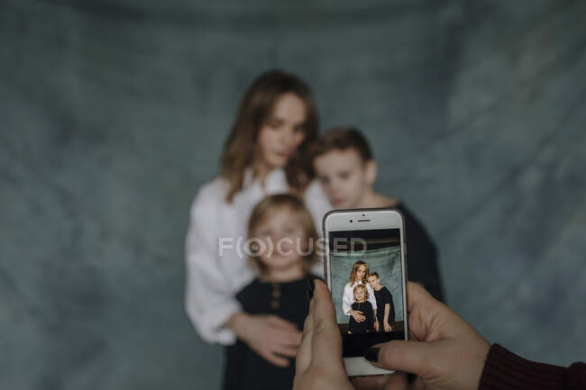 Рука жінок, які фотографують сім'ю через смартфон вдома. — стокове фото