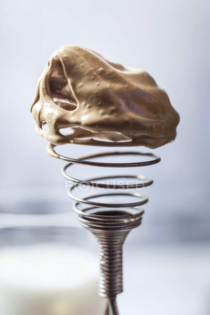 Close-up of wire whisk covered in dalgona coffee cream — Stock Photo