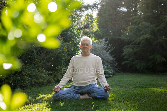 Hombre mayor meditando en el jardín - foto de stock