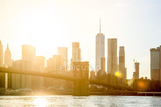 Estados Unidos, Nueva York, Nueva York, Puesta de sol iluminando el puente de Brooklyn y el horizonte de Manhattan - foto de stock