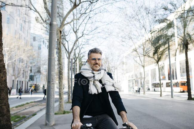 Uomo d'affari dai capelli grigi in bicicletta in città — Foto stock