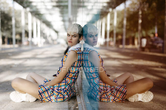Retrato de una adolescente usando un vestido colorido apoyado en el cristal - foto de stock