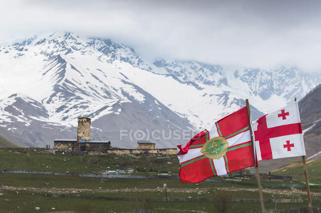 Грузія, Сванеті, Ушулі, грузинські прапори, що пурхають перед середньовічним селом. — стокове фото