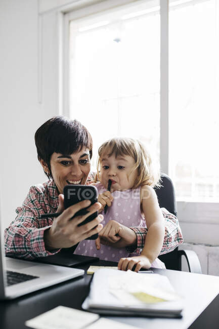 Mother and daughter using smartphone at home — Stock Photo