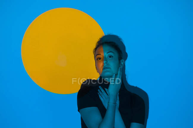 Mujer joven moviéndose en luz azul delante del círculo amarillo - foto de stock