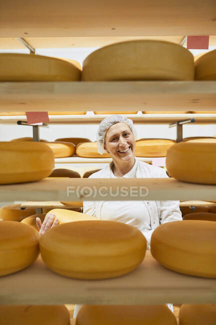Fromagerie, ouvrière avec meule à fromage dans le cellier — Photo de stock