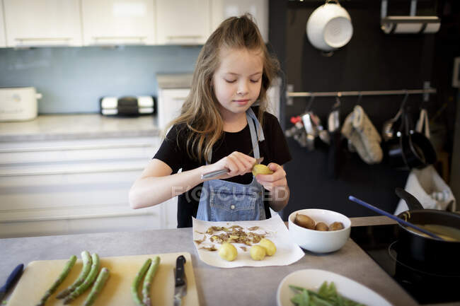 Porträt eines Mädchens, das in der Küche Kartoffeln schält — Stockfoto