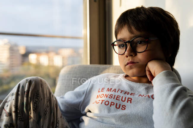 Портрет скучающего мальчика, сидящего дома на кресле — стоковое фото