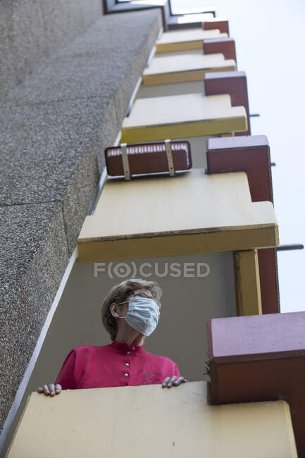 Старшая женщина в маске на балконе, дом престарелых — стоковое фото