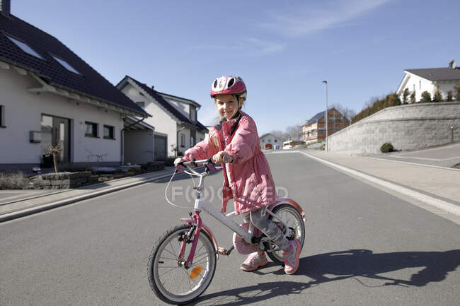 Portrait of little girl with bicycle in housing area — Stock Photo