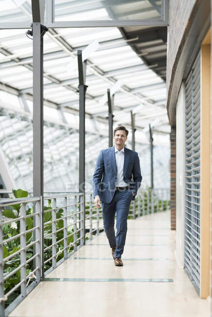 Uomo d'affari fiducioso che cammina su galleria di atrio verde — Foto stock