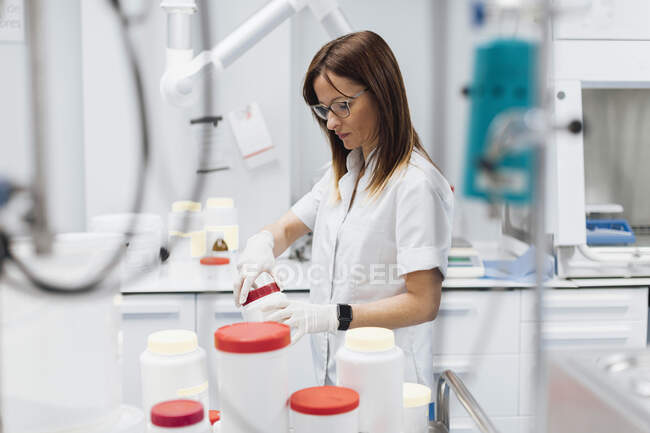 Confident female doctor opening jar while standing at laboratory — Stock Photo