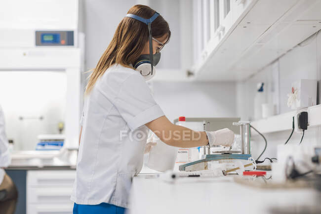 Confident mature female healthcare worker using weight scale at lab — Stock Photo