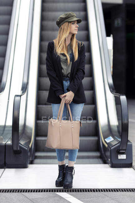 Портрет блондинки з сумкою, що стоїть спереду на ескалаторі — стокове фото