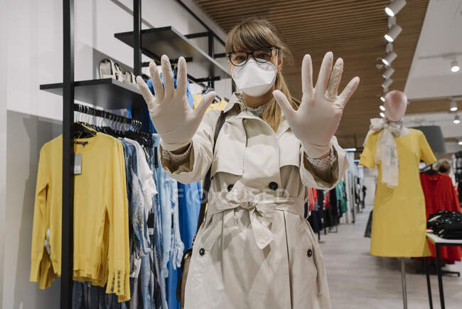 Женщина в маске для лица и одноразовых перчатках в магазине мод — стоковое фото