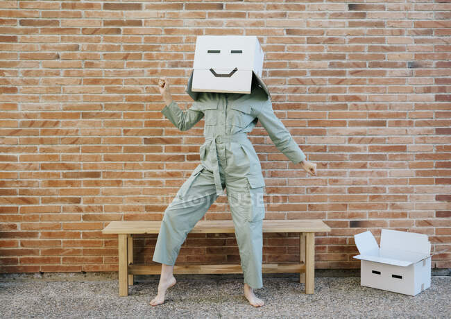 Frau im Karton mit glücklichem Gesicht tanzt vor Bank — Stockfoto
