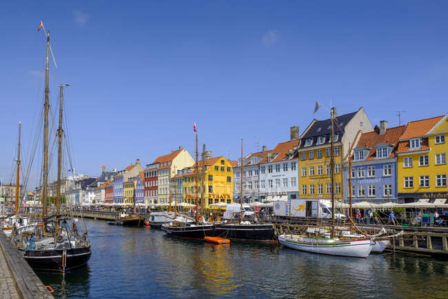 Denmark, Copenhagen, Boats moored along Nyhavn canal with colorful townhouses in background — Stock Photo