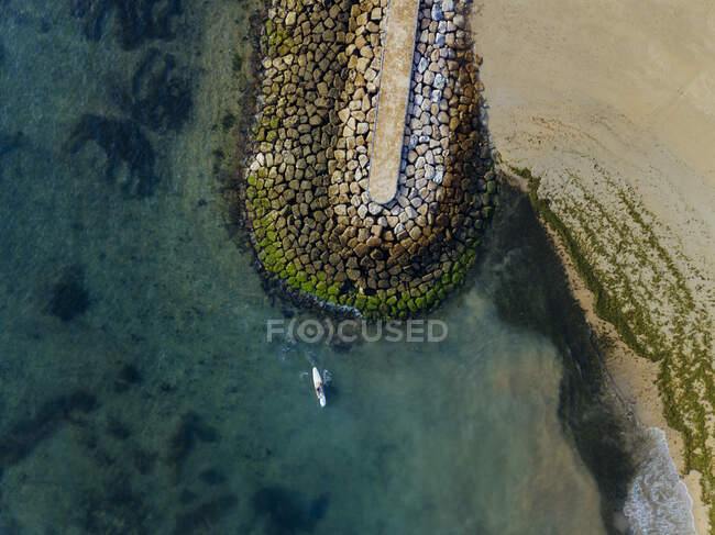 Indonesia, Bali, Sanur, Vista aérea del surfista solitario frente a la costa rocosa - foto de stock