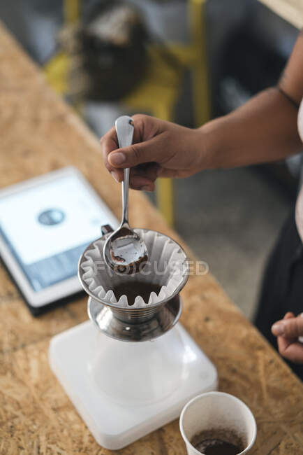 Primer plano de la mujer que trabaja en un tostado de café preparando café fresco filtrado - foto de stock