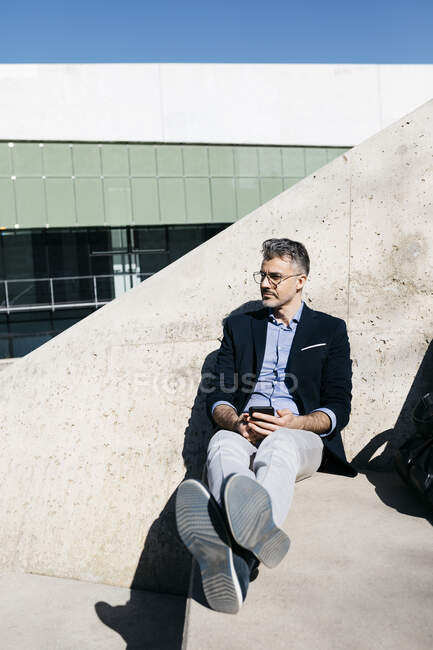 Uomo d'affari dai capelli grigi seduto sulle scale della città — Foto stock