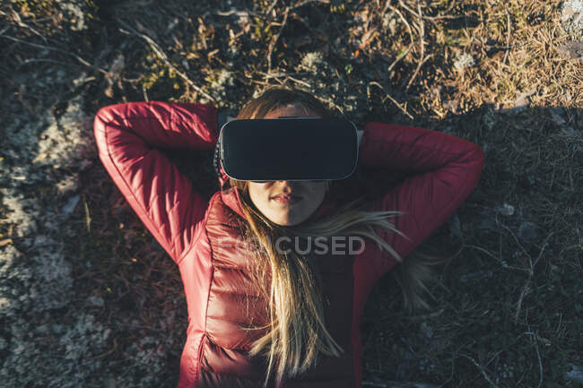 Junge Frau mit VR-Brille liegt in der Natur auf dem Boden — Stockfoto