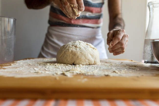 Crop view of man spreading flour on dough — Stock Photo