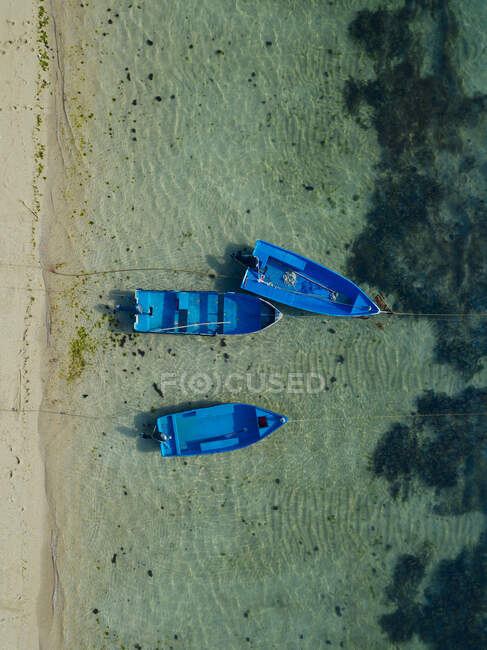 Indonesia, Bali, Sanur, Vista aérea de barcos azules amarrados frente a la playa costera de arena - foto de stock