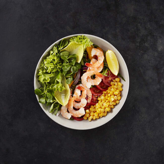 Bowl with fresh corn, tomatoes, lemon, shrimps, corn salad, chicory and lollo bionda lettuce — Stock Photo