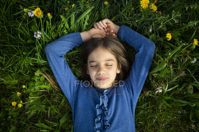 Retrato de chica con los ojos cerrados relajándose en un prado en primavera - foto de stock