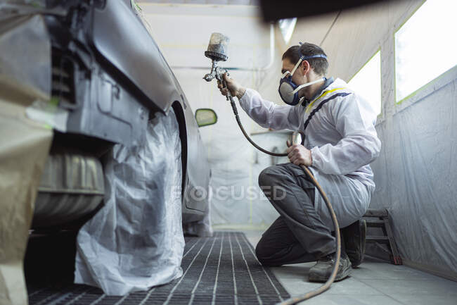 Body painter painting car in paint booth — Stock Photo