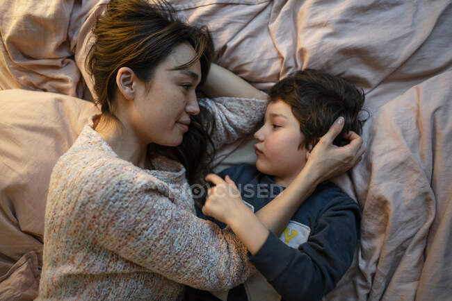 Mère et petit fils se relaxent ensemble sur le lit — Photo de stock