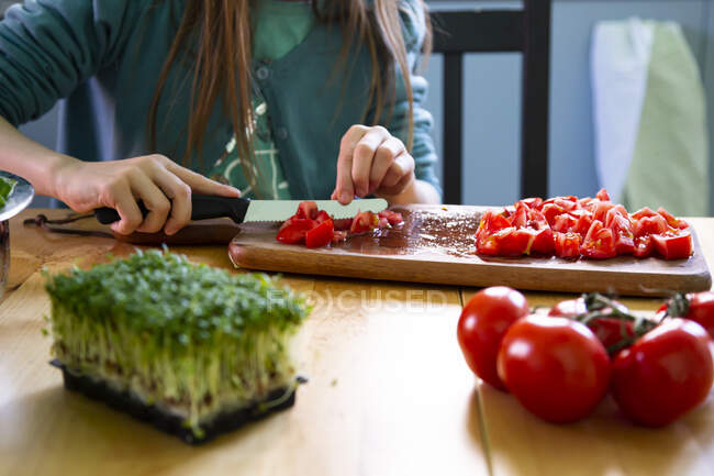 Girl cutting tomatoes on chopping board — Stock Photo