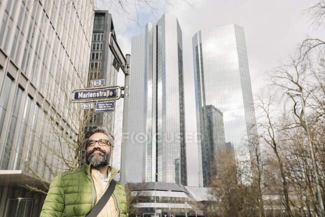 Retrato de un hombre sonriente frente a rascacielos, Frankfurt, Alemania - foto de stock
