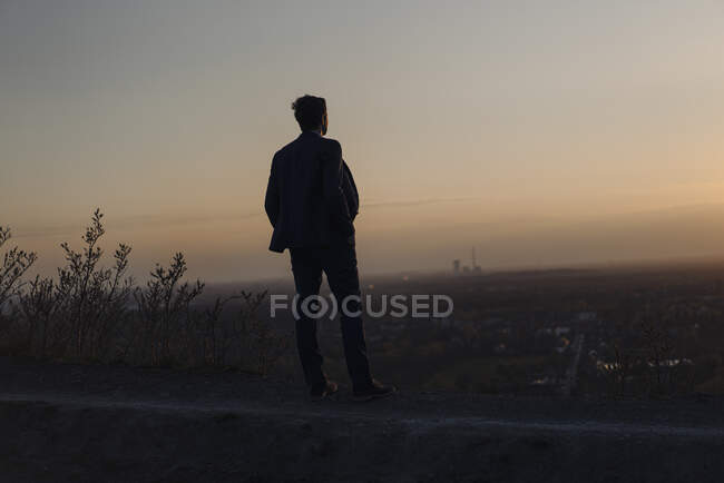 Maturo uomo d'affari in piedi su un disuso miniera punta a tramonto guardando vista — Foto stock