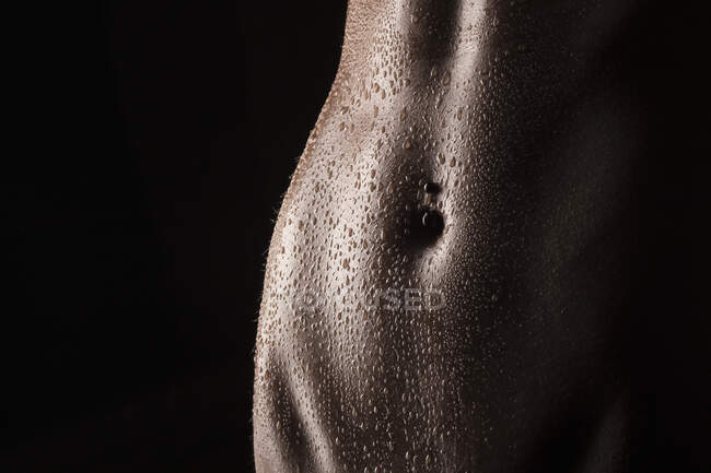 Gotas de agua del vientre desnudo de una mujer joven - foto de stock
