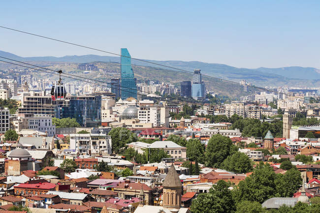 Cityscape contra montanhas contra céu limpo durante o dia ensolarado, Tbilisi, Geórgia — Fotografia de Stock