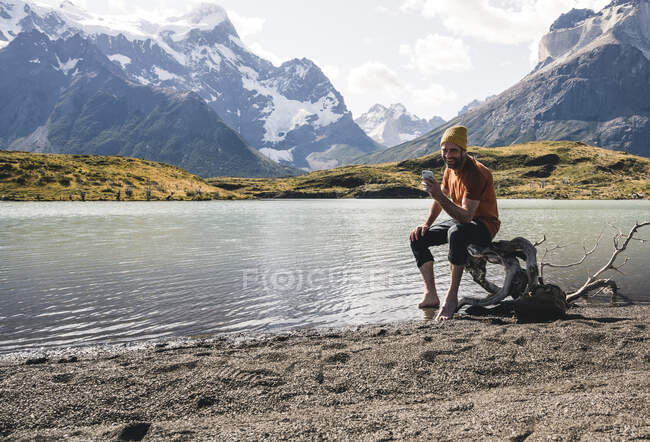 Uomo che utilizza il cellulare nel paesaggio montano sul lungolago nel Parco Nazionale di Torres del Paine, Patagonia, Cile — Foto stock