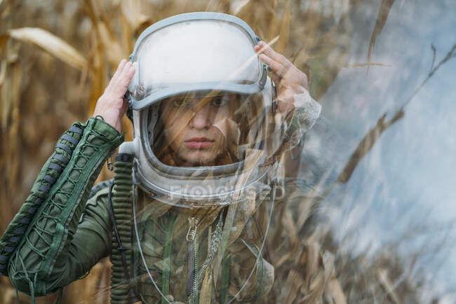 Joven astronauta de pie en el campo de maíz marchitado - foto de stock
