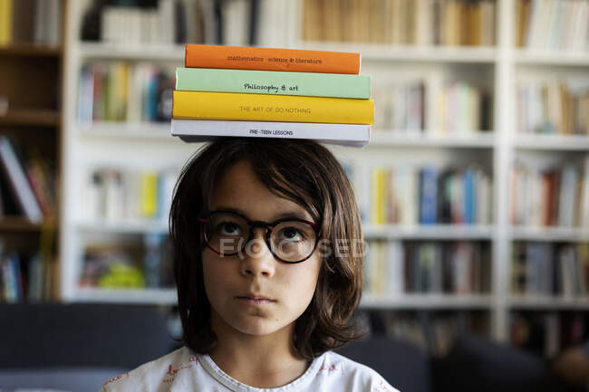 Porträt eines Jungen, der einen Stapel Bücher auf dem Kopf balanciert — Stockfoto