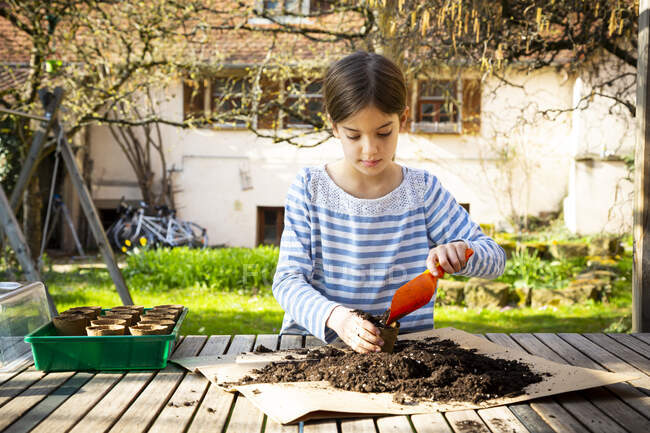 Mädchen füllt Pflanztöpfe mit Erde und Samen — Stockfoto