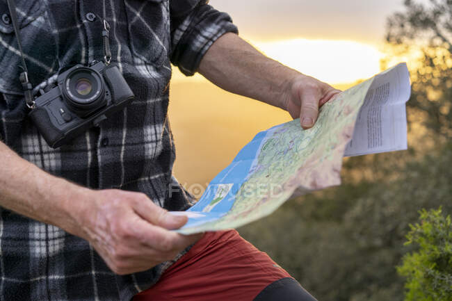 Primo piano dell'uomo che tiene una mappa durante un viaggio a piedi — Foto stock