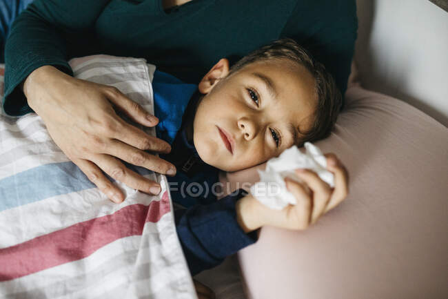 Portrait of sick little boy lying in bed — Stock Photo