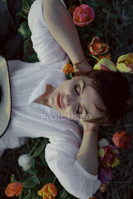 Retrato de mulher com os olhos fechados deitado no chão entre tulipas — Fotografia de Stock