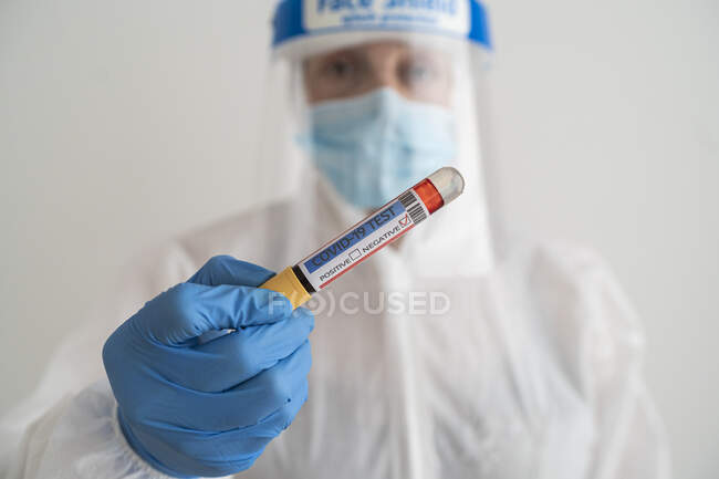 Mulher em desgaste protetor segurando teste covid-19 negativo — Fotografia de Stock