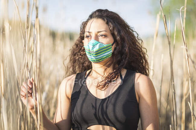 Portrait de jeune femme debout parmi roseau portant un masque de protection — Photo de stock